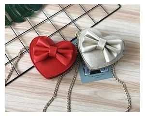 Close-up of heart-shaped crossbody bags with large bows and gold chain straps