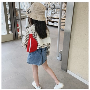 Rear view of a red canvas children's waist bag with adjustable strap on a girl model