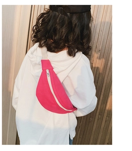 Close-up of pink canvas waist bag with silver zipper and white strap on a child's back