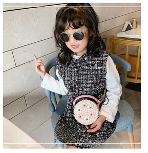 Détail du sac rond tissé pour enfant avec poignée en cuir rose et chaîne dorée