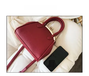 Detail view of red shell bag with gold clasp and smartphone for size comparison