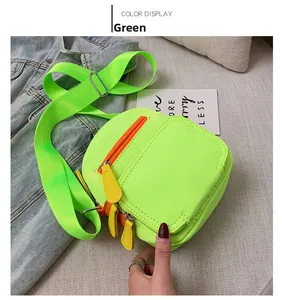 Detail of neon green crossbody square bag featuring orange zippers and wide shoulder strap