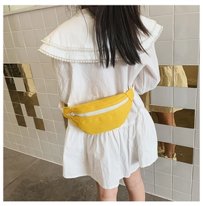 Rear view of a girl wearing a bright yellow canvas waist bag with white adjustable strap