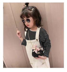 Détail d'un sac bandoulière enfant en tweed noir avec fleurs et bandoulière dorée