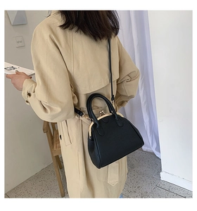 Classic black litchi leather shell bag with gold clasp shown on a trench coat model
