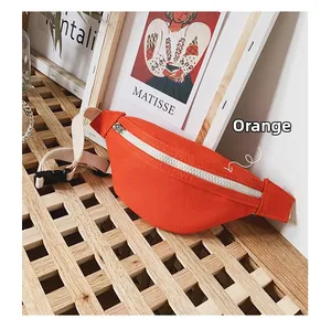 Close-up of orange canvas kids chest bag with silver zipper on a wooden table surface