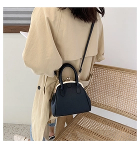 Model wearing a black lychee texture shell bag with gold clasp and slender strap