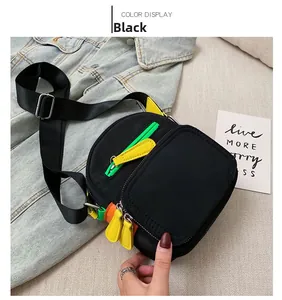 Close-up of black nylon crossbody bag with vibrant neon zipper pulls on denim jacket