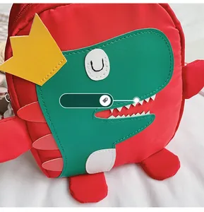 Détail du sac à dos dinosaure rouge avec coutures fines et broderie de dessin animé