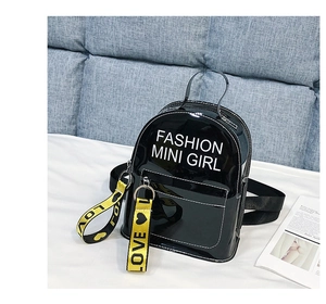 Détail du mini sac à dos en cuir verni noir avec texte blanc et sangle jaune love