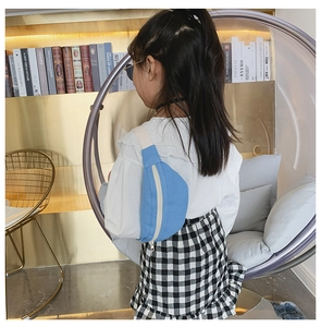 Detail of blue canvas kids chest bag with contrast strap worn by a child in home setting