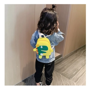 Vue arrière d'un enfant portant le sac à dos dinosaure jaune avec motif de dessin animé