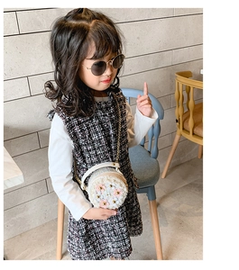 Détail d'un petit sac rond pour enfant avec fleurs et bandoulière dorée sur modèle