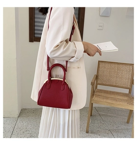 Deep red leather seashell handbag with gold hardware and top handle shown on a model