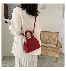 Chic red shell bag in lychee texture worn crossbody showing stylish daily carry size