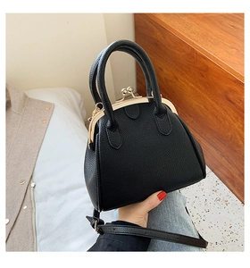 Detail shot of a black vintage shell handbag with a gold kiss-lock and top handles