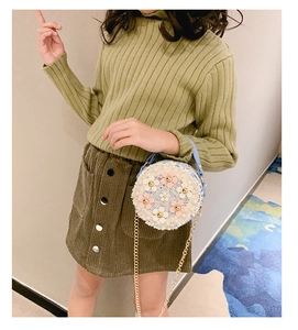 Sac rond en tweed à fleurs pour fille porté par un mannequin avec chaîne dorée et perles
