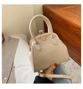 Detail of beige pebble leather handbag with vintage metal clasp closure and handle