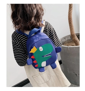 Enfant portant un sac à dos dinosaure bleu avec broderie verte et couronne jaune