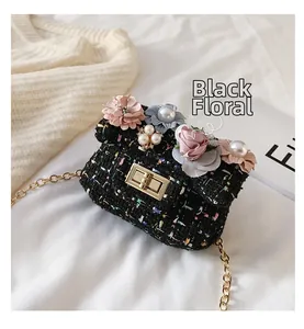 Dettaglio della mini borsa a tracolla in tweed nero con fiori in tessuto e catena oro