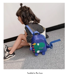 Détail du sac à dos dinosaure bleu pour enfants avec motifs verts et nageoires rouges
