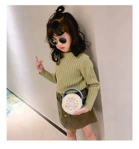 Détail d'un enfant portant un sac tissé cylindrique avec fleurs et bandoulière chaîne