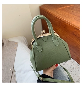 Detail of sage green pebble leather shell bag with gold metal clasp and top handle