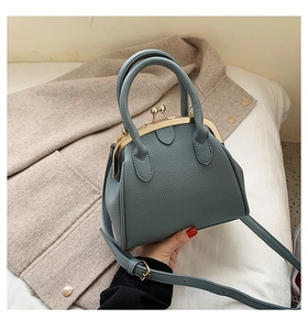 Detail of blue textured leather shell bag with gold hardware and doctor bag closure