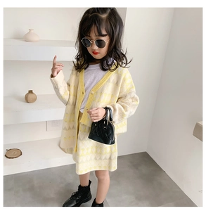 Close-up of girls knitted yellow diamond pattern cardigan and matching skirt outfit