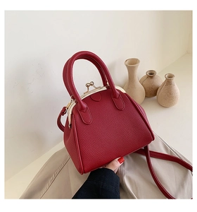 Detail of red lychee grain leather handbag with vintage metal clasp and top handle
