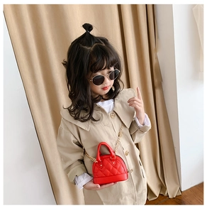 Close-up of red quilted mini shell bag with gold chain strap on a model's beige coat