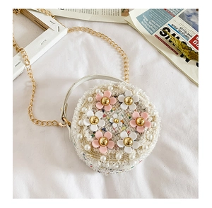 Détail d'un sac rond en tweed pour filles avec fleurs en résine rose, perles et chaîne d'or