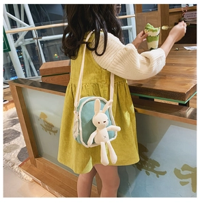 Dettaglio di un bambino con borsa a tracolla verde acqua e un simpatico coniglio peluche