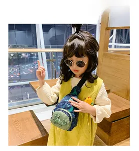 Detailed view of children's navy dinosaur chest bag with 3D green accent on model