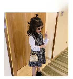 Detail of a child wearing a tweed dress paired with a golden quilted chain shell bag