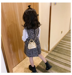 Classic quilted gold mini round crossbody bag paired with a tweed dress and leather boots