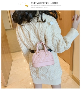 Pink quilted shell-shaped mini crossbody bag with gold chain strap shown on a child model