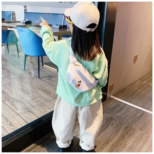 Detailed view of kids white chest bag with cartoon print on green sweatshirt