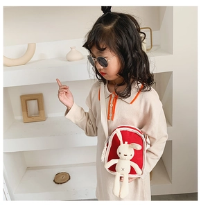 Dettaglio di una borsa a tracolla rossa per bambini in tela con un peluche di coniglio