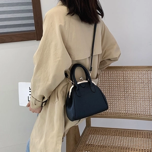 Classic black leather doctor bag with gold kiss lock worn with a khaki trench coat