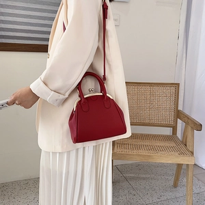 Red retro leather shell bag with gold clasp shown on a model in a warm setting