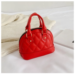 Detail view of red quilted mini shell bag with golden zipper on soft fabric background