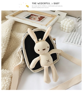 Dettaglio del peluche a forma di coniglio sulla borsa a tracolla in tela nera per bambini