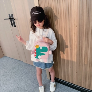 Sac à dos rose dinosaure pour enfant porté par un petit modèle sur fond bois