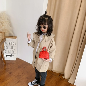 Girl wearing a stylish beige trench coat and a red heart-shaped quilted handbag