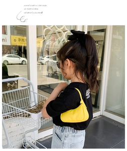 Photo en extérieur d'un mini sac hobo jaune vif porté par un enfant dans la rue