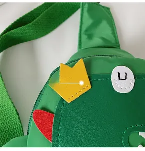 Detail view of green dinosaur kid's crossbody bag with yellow crown and nylon texture