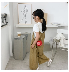 Detail showing red basketball-shaped chain purse with white T-shirt and yellow jumpsuit