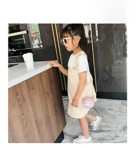 Close-up of stylish pink basketball shaped chain bag paired with girls denim dress