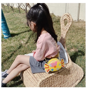 Detail showing a yellow candy-shaped crossbody bag with colorful polka dots on a child